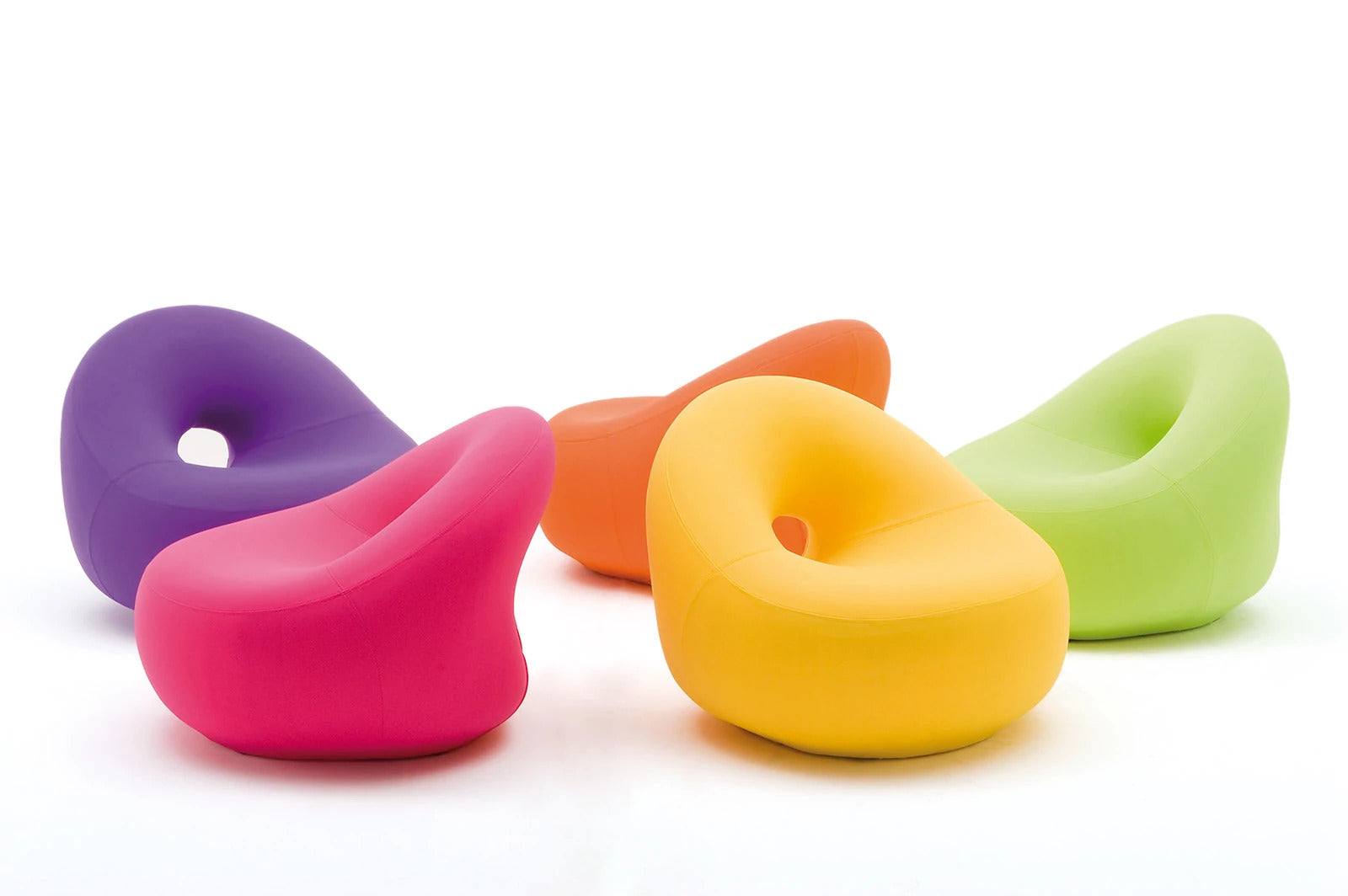 Five modern, organic-shaped Bolle Armchairs in vibrant colors including purple, pink, orange, yellow, and green, arranged on a clean white background. Giovannetti Collezioni.
