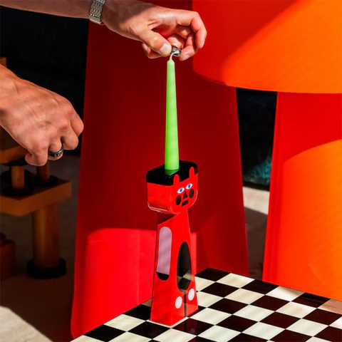 Qeeboo Red cat-shaped toothbrush holder with a green toothbrush on a checkered floor.