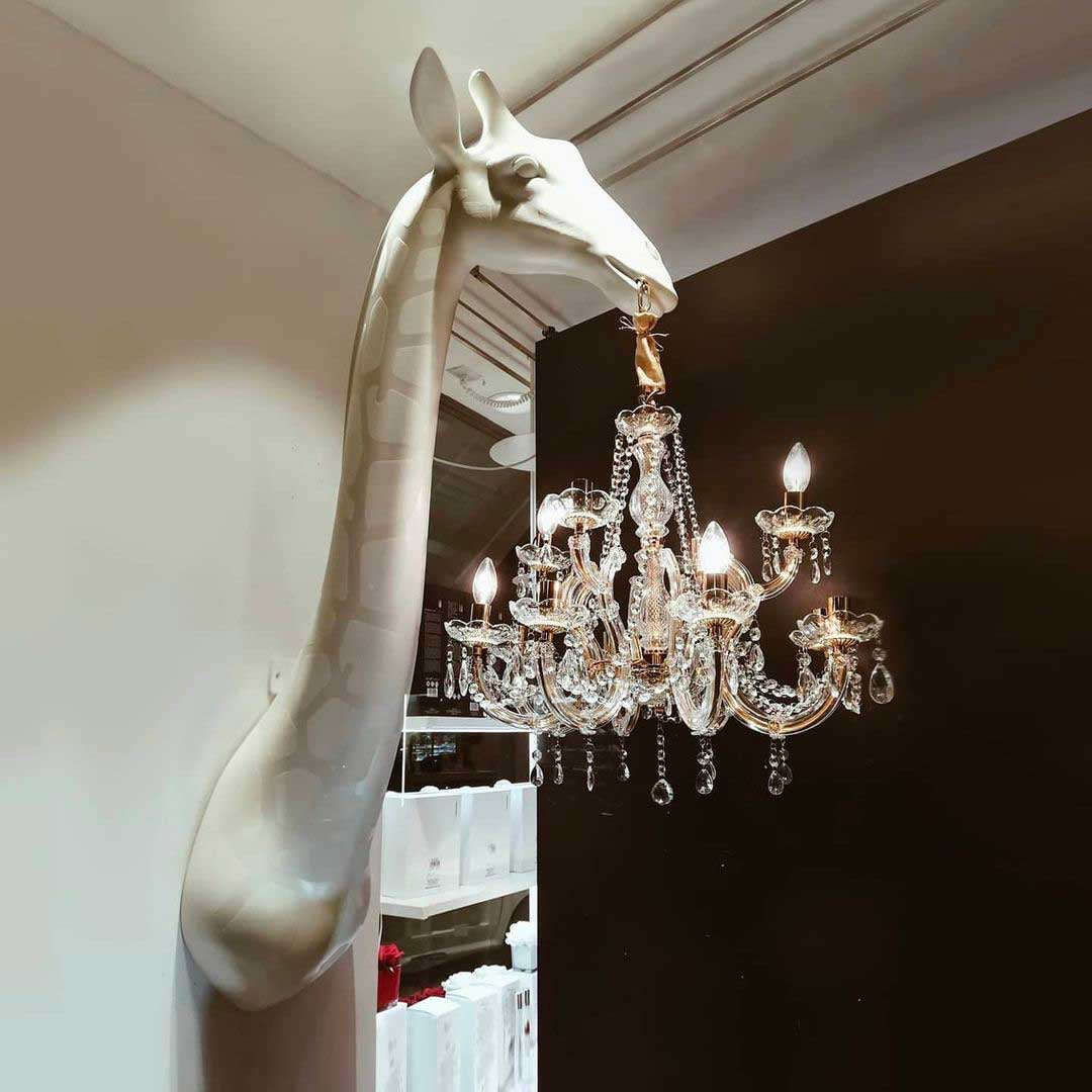 Giraffe-shaped chandelier hanging from a wall by Qeeboo