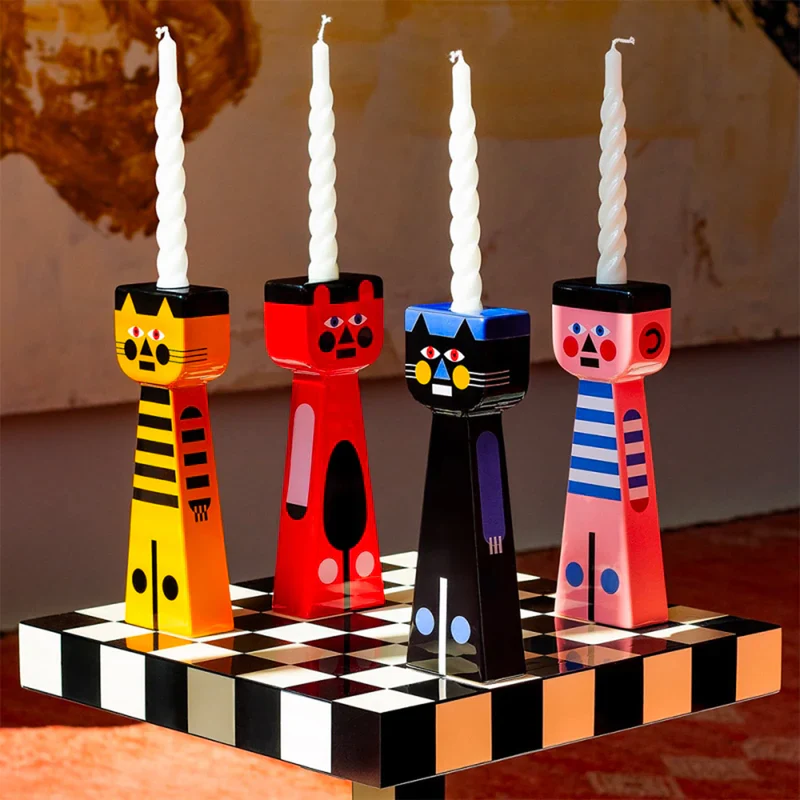 Qeeboo Marco Oggian designer candlesticks shaped as stylized cats holding white twisted candles on a checkered surface