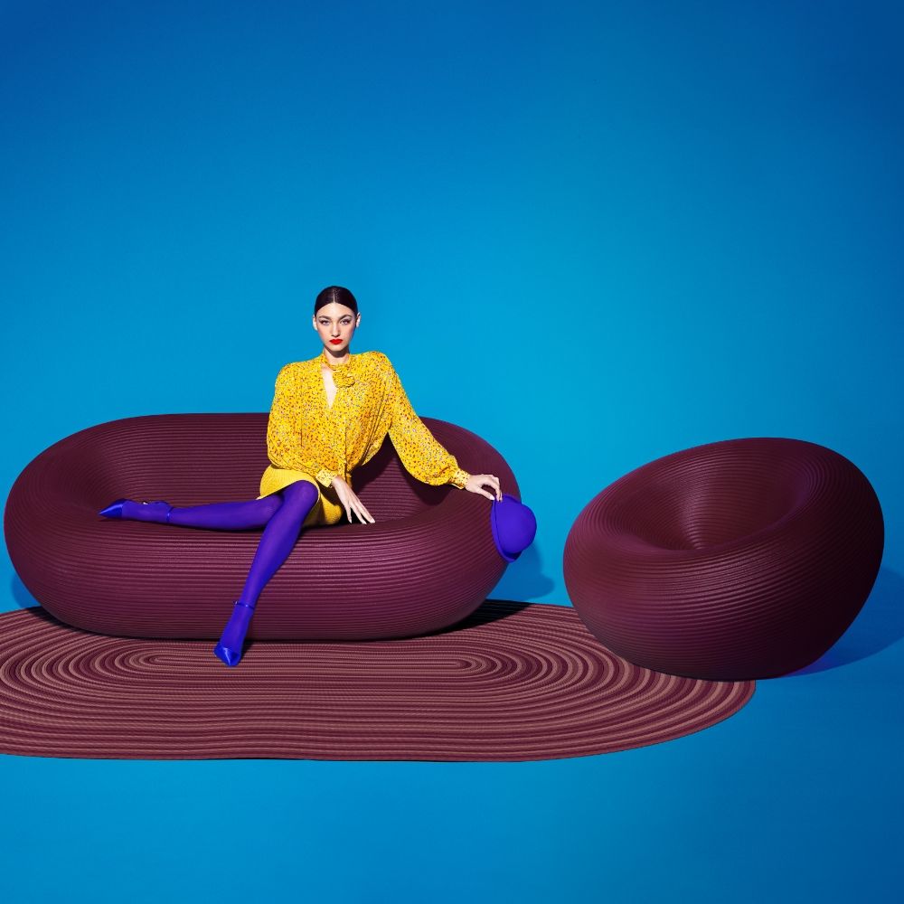 Qeeboo Nami indoor armchair and sculptural sofa in deep purple with bold artistic styling against bright blue background
