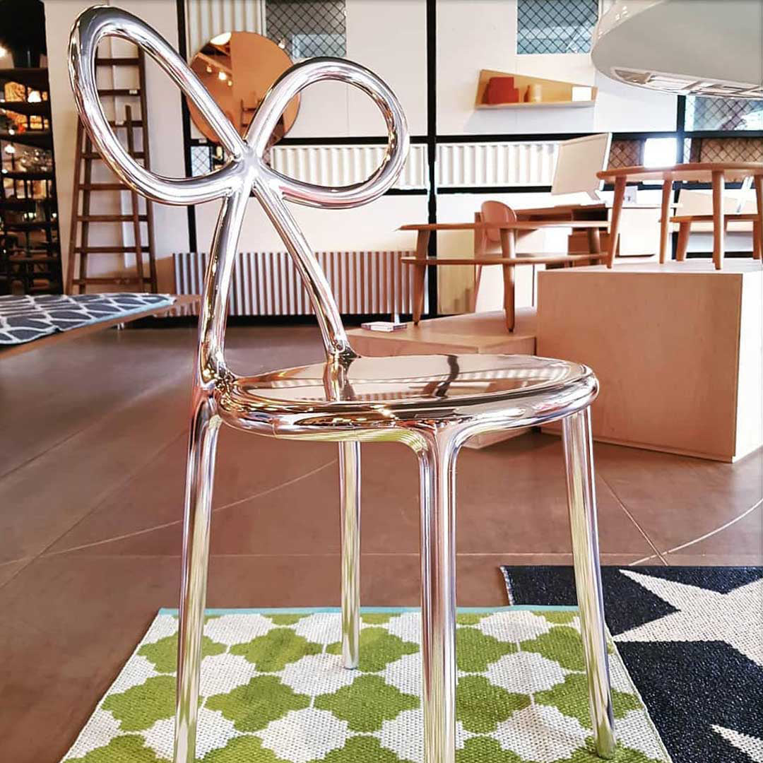 A glossy, highly reflective silver Ribbon metallic chair with a sculptural looped back and curved legs by Qeeboo