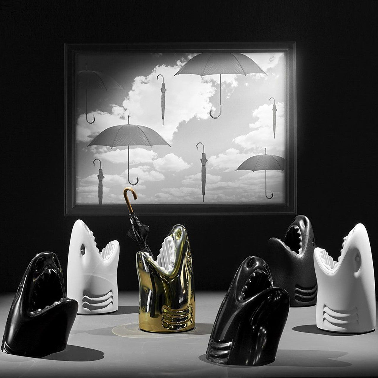 Shark-shaped Qeeboo Killer umbrella stands in black, white, and gold arranged in a semicircle