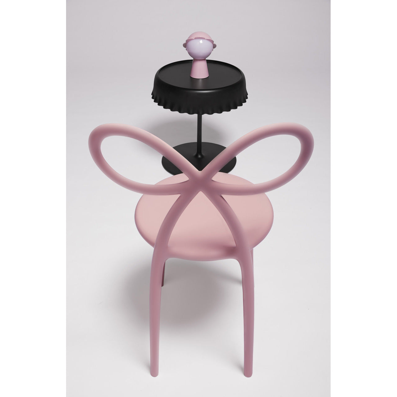 Qeeboo Pink Ribbon Chair placed in a bright contemporary dining room interior.